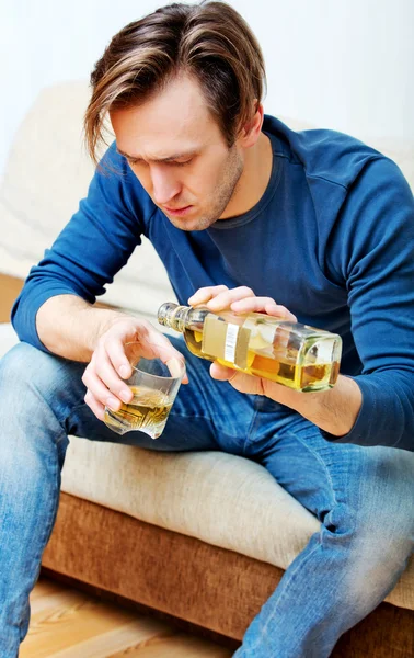 Drunk man sitting on couch and drinking whiskey