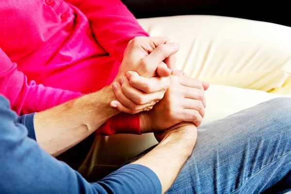 Mother and son sitting on couch and holding hands