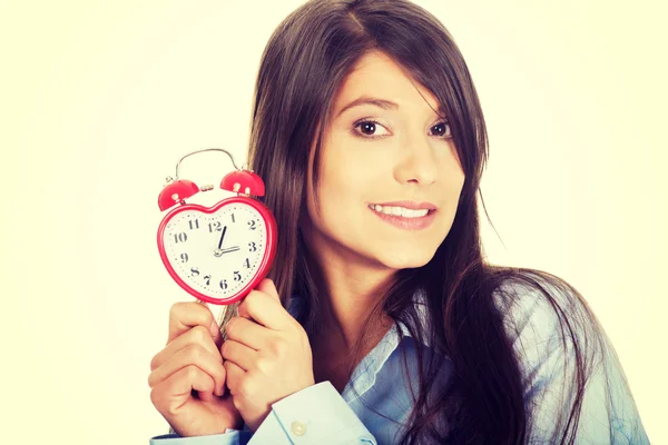 Young woman in big shirt holding alarm clock.