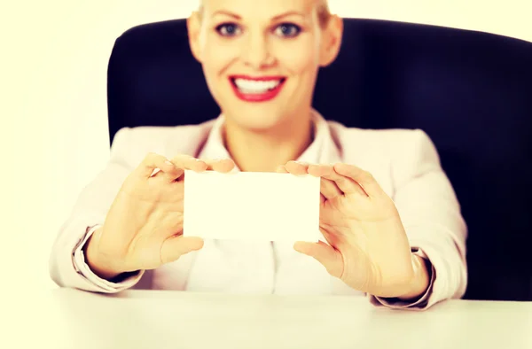 Smile business woman sitting behind the desk and holding empty buisiness card