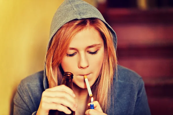 Teenage woman drinking beer and smoking cigarette