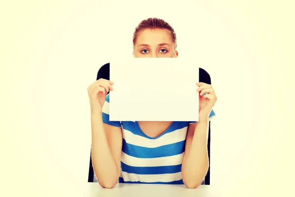Teenage woman covering face with paper card
