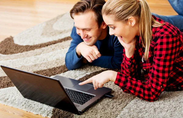 Happy couple lying on the floor with laptop