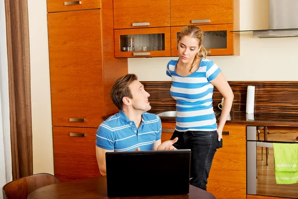 Man watching something on laptop, his wife is angry