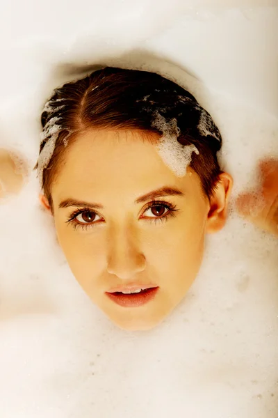Young woman washing hair in bath