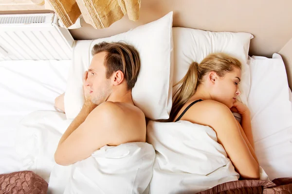 Young offended couple lying back to back in bed