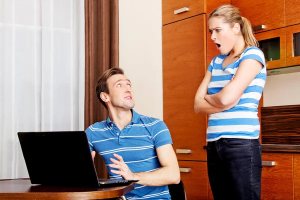 Man watching something on laptop, his wife is angry