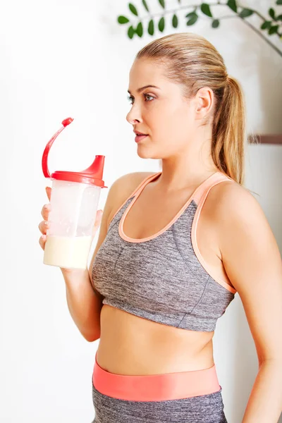 Young sporty woman drinking protein shake