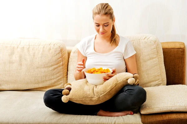 Young woman watching TV and eating chips