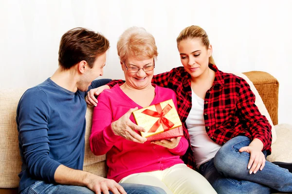 Happy family - couple with old woman who holding gift box