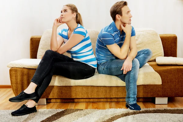 Offended couple sitting back to back on sofa