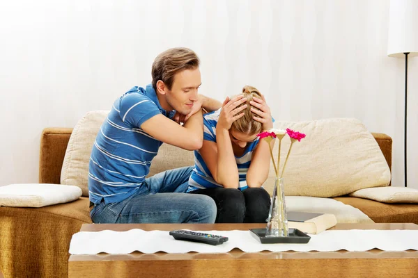 Man comforting his upset partner in living room