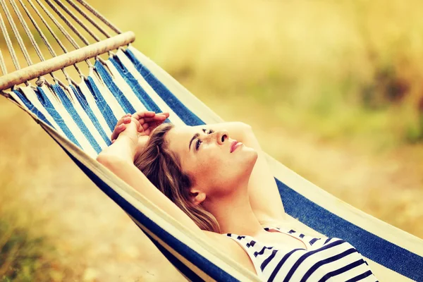 Young blonde woman resting on hammock