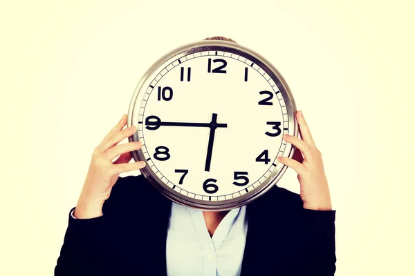 Business woman covering face with a clock