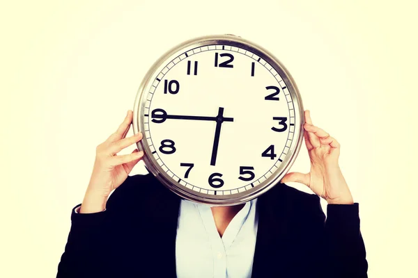 Business woman covering face with a clock