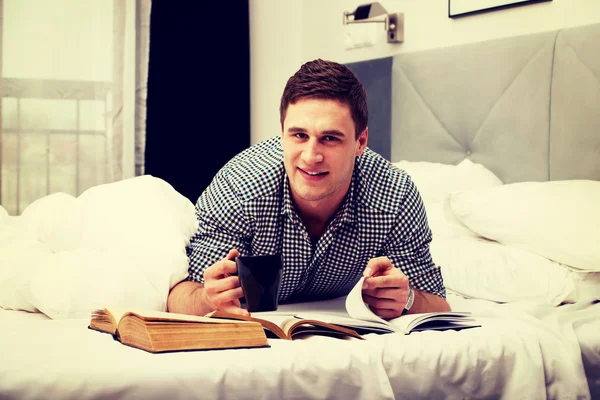 Happy man with a book in his bed.