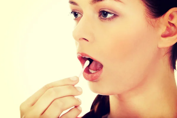 Young woman putting ear stick into mouth
