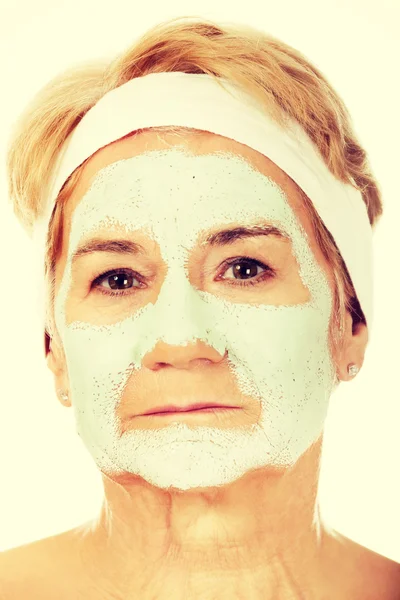 Relaxed elderly woman in facial mask