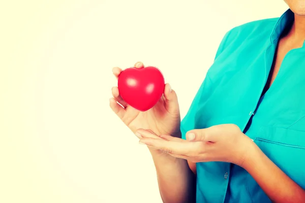 Young female doctor or nurse holding heart toy