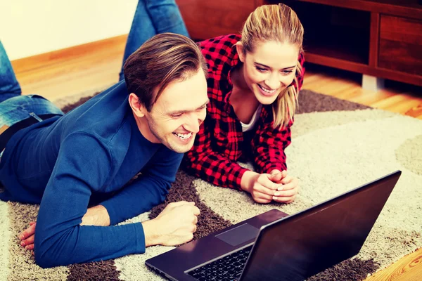 Happy couple lying on the floor with laptop