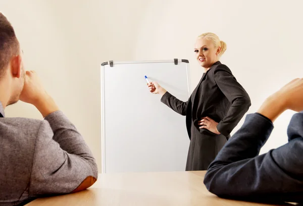 Smiling businesswoman drawing a graph for her colleagues on the whiteboard
