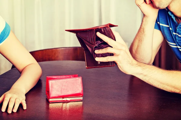 Worried couple sitting at the table with empty wallets