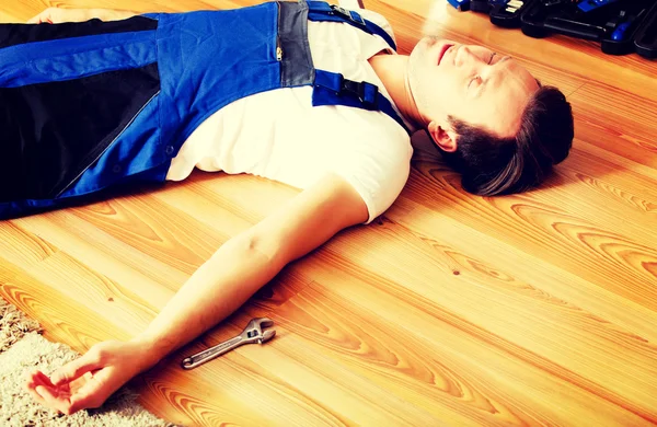 Young handyman fell from a ladder and lies on the floor