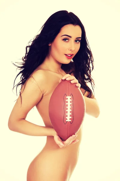 Undressed woman holding rugby ball.