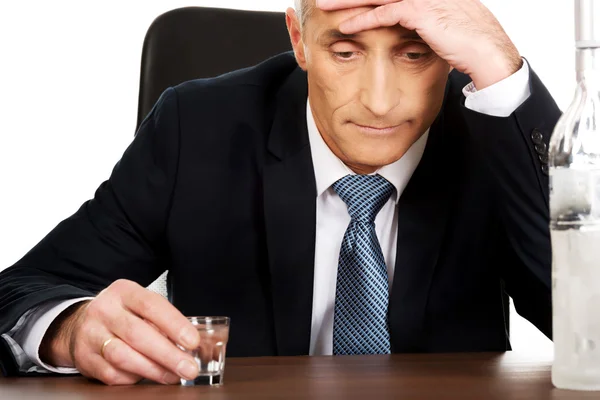 Overworked man drinking vodka in office