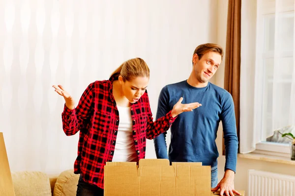Couple unpaking boxes, stressed woman looking to inside