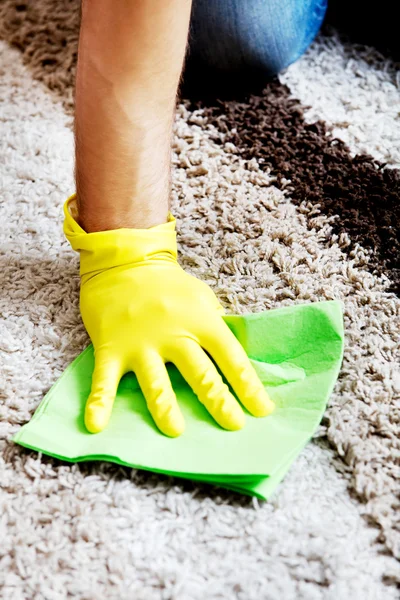 Man in yellow gloves cleaning carpet