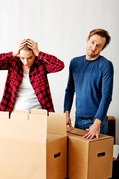 Couple unpaking boxes, woman looking to inside and aghast holding her head