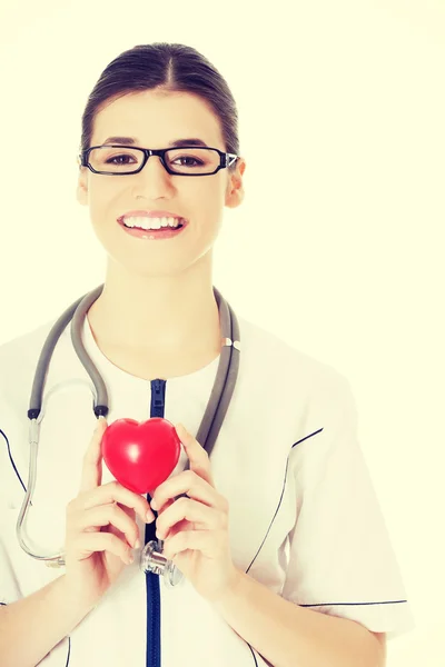 Beautiful young female doctor holding a heart.