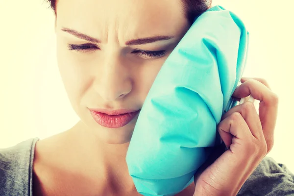 Young woman with toothache and ice bag.