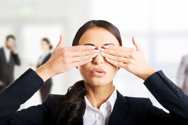 Businesswoman covering eyes with hands.