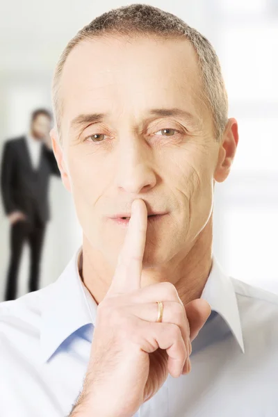 Mature man with finger on lips.