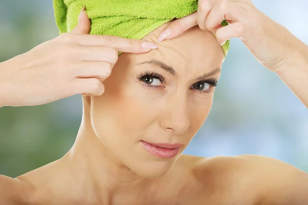 Woman checking wrinkles on her forehead.