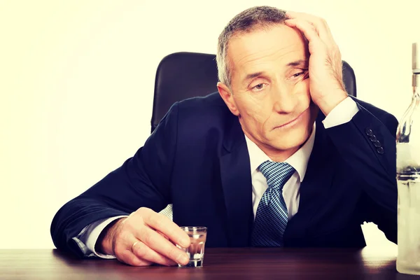 Overworked man drinking vodka in office