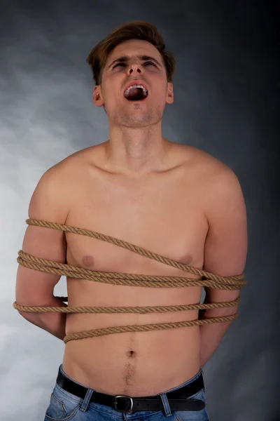 Tortured man tied with a rope.