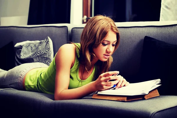 Young woman learning to exam on a sofa.