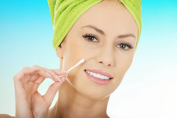 Woman removing make up with cotton bud.