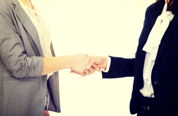 Two women in office outfits giving handshake.