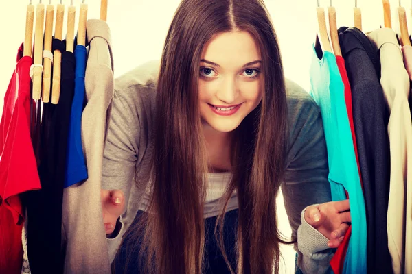 Teen woman between clothes on hanger.