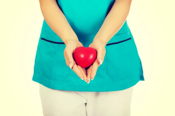 Nurse or female doctor holding red heart.