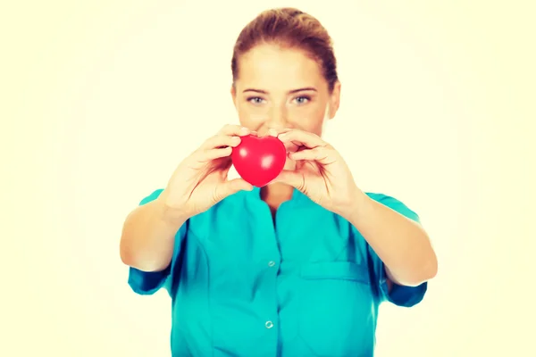 Young female doctor or nurse holding heart toy