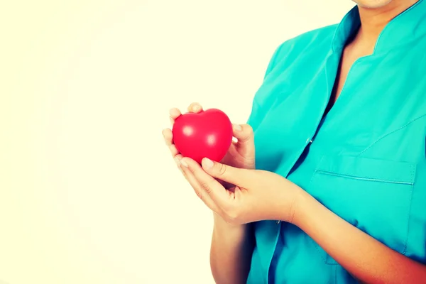 Young female doctor or nurse holding heart toy