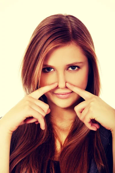 Young woman pinches nose with fingers hands looks