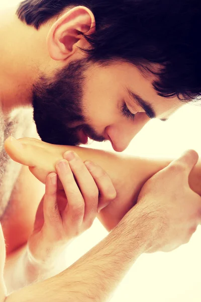 Handsome man kissing womans feet.