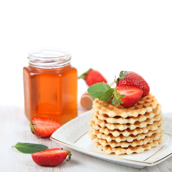 Jar of honey, ripe strawberries and waffles