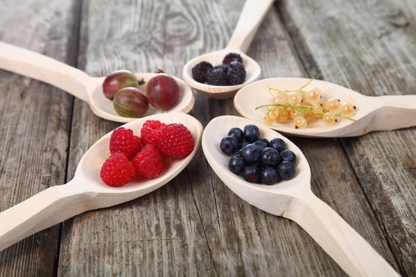 Different ripe berries in a wooden spoons